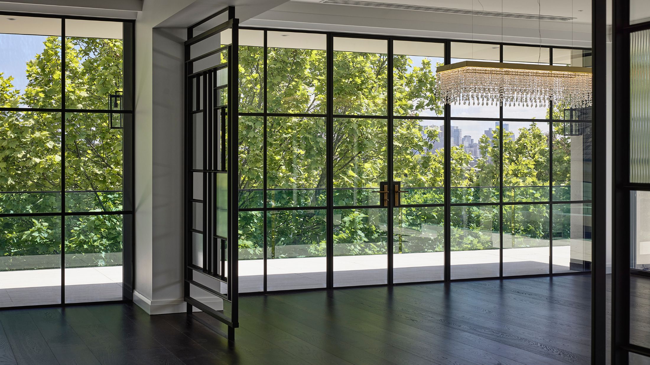 Expansive Metro steel-framed windows and doors overlooking trees at Brivana Residence.